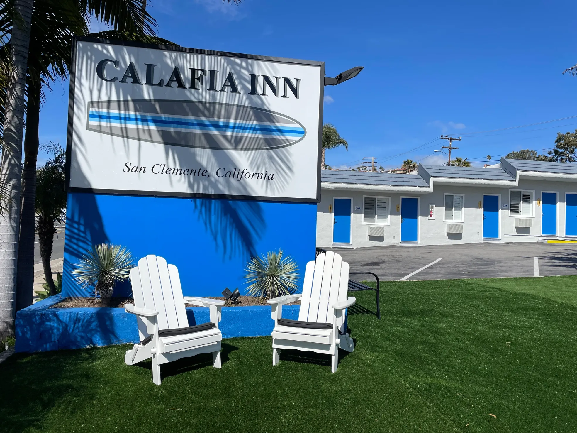 The Calafia Inn sign with white Adirondack chairs and palm trees