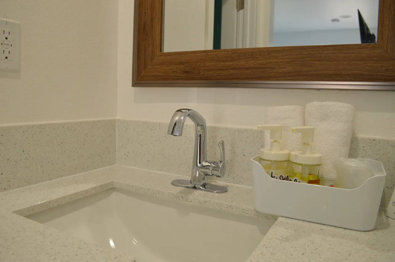 Standard room bathroom vanity with a wood-framed mirror, towels and toiletries